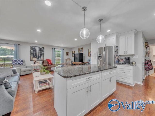 kitchen featuring recessed lighting, dark stone countertops, stainless steel refrigerator with ice dispenser, and open floor plan