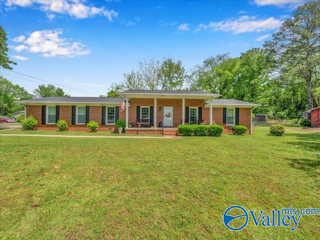ranch-style home featuring covered porch, a front lawn, and brick siding