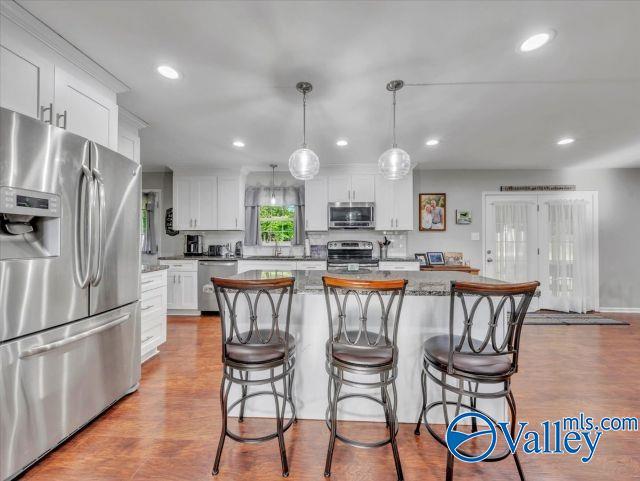 kitchen featuring appliances with stainless steel finishes, a kitchen breakfast bar, dark wood finished floors, and white cabinetry