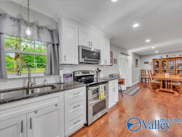 kitchen with appliances with stainless steel finishes, a sink, dark stone counters, recessed lighting, and white cabinetry