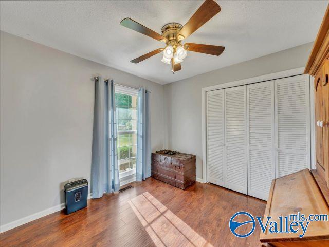 unfurnished bedroom with baseboards, ceiling fan, wood finished floors, and a closet