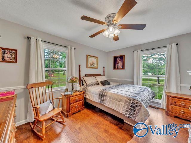 bedroom with baseboards, multiple windows, light wood-type flooring, and ceiling fan