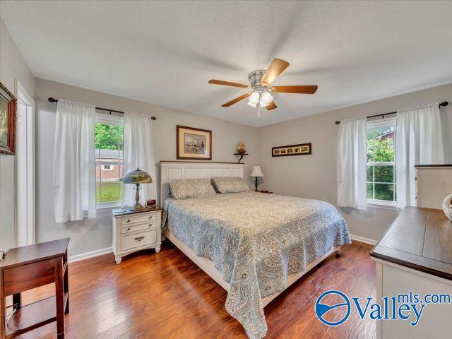 bedroom with baseboards, multiple windows, and dark wood-type flooring