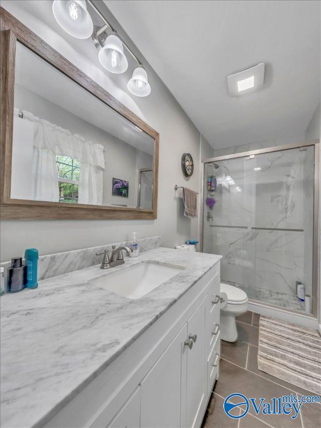 full bathroom featuring vanity, tile patterned flooring, a stall shower, and toilet