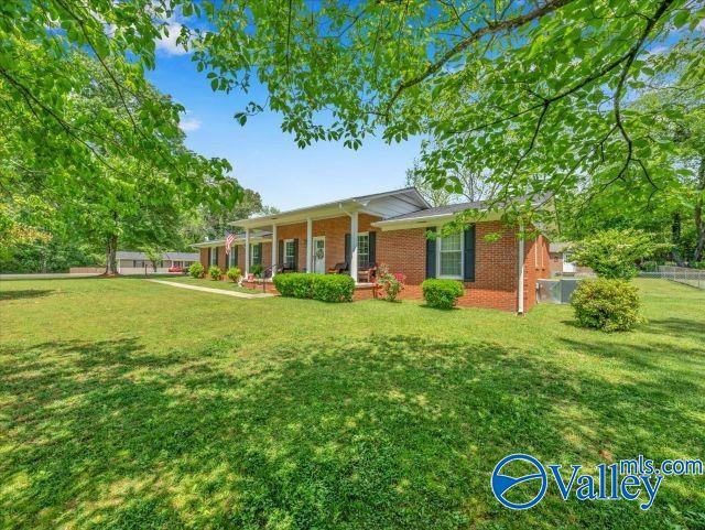 view of front of house featuring covered porch, brick siding, and a front yard