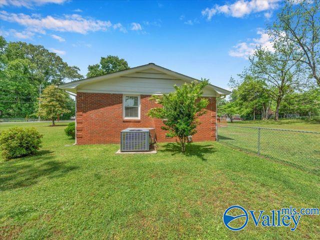 back of property featuring central air condition unit, fence, a yard, and brick siding