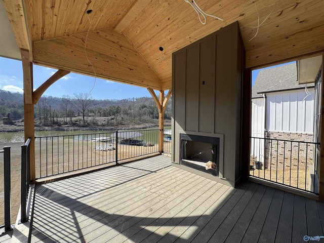 deck with a water view and exterior fireplace