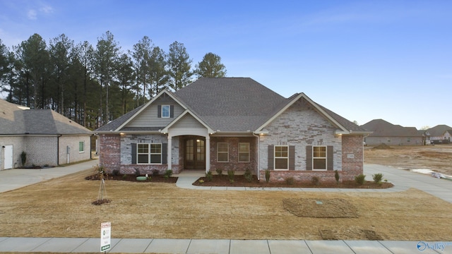 craftsman-style house with brick siding and a shingled roof