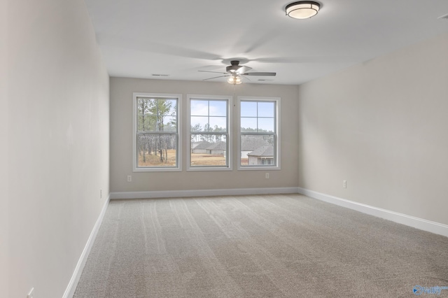 spare room featuring a ceiling fan, visible vents, baseboards, and light carpet