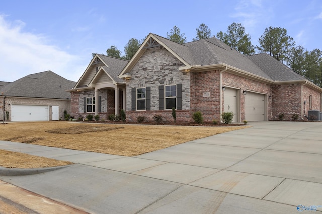 craftsman-style home with cooling unit, driveway, an attached garage, a shingled roof, and brick siding