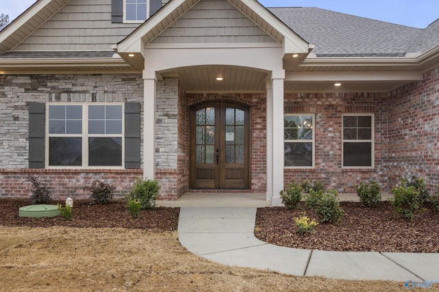 property entrance with french doors, brick siding, and roof with shingles
