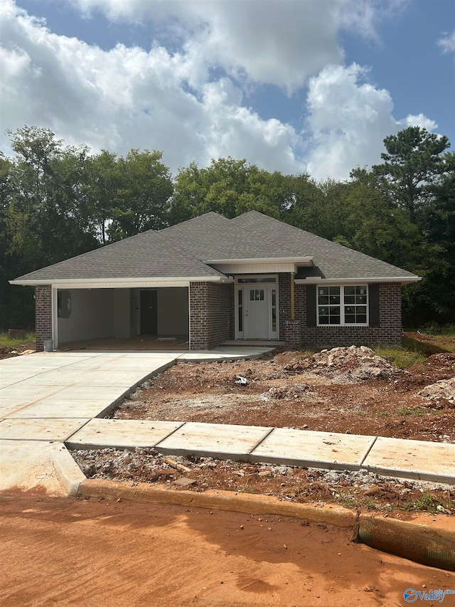 view of front of house featuring a garage, brick siding, roof with shingles, and concrete driveway