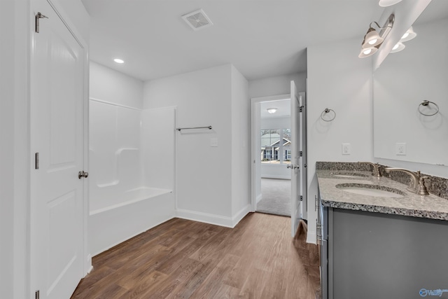 bathroom with visible vents, baseboards, double vanity, wood finished floors, and a sink