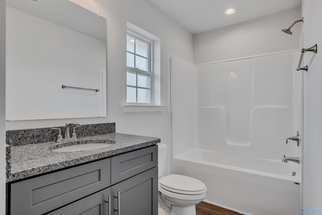 bathroom with wood finished floors, toilet, shower / washtub combination, and vanity