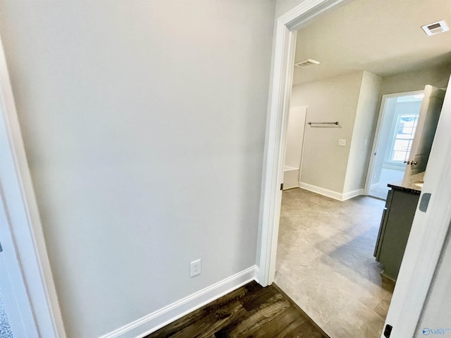 hallway with dark wood-style floors, visible vents, and baseboards