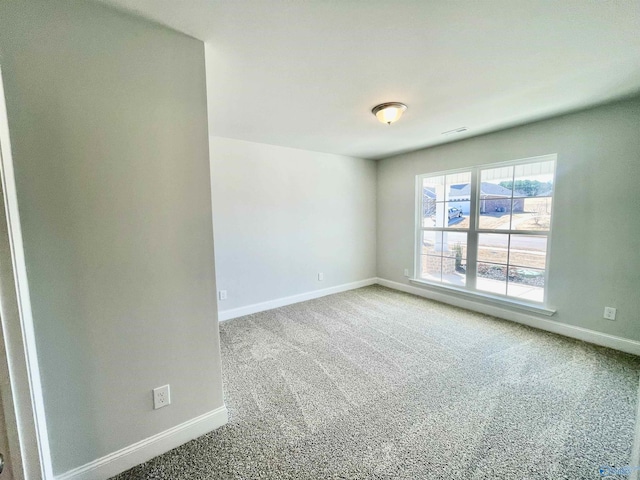 carpeted empty room featuring baseboards