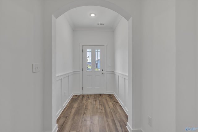 doorway featuring crown molding and light wood-type flooring