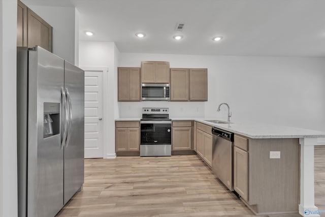 kitchen with light hardwood / wood-style flooring, kitchen peninsula, sink, appliances with stainless steel finishes, and light stone counters