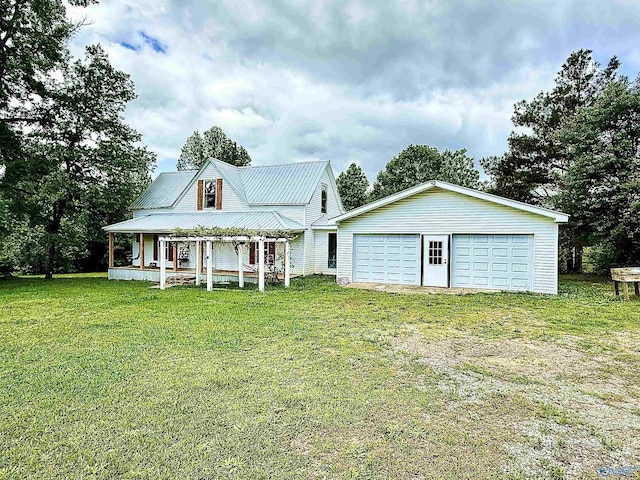 back of property with covered porch, metal roof, a lawn, a garage, and an outdoor structure
