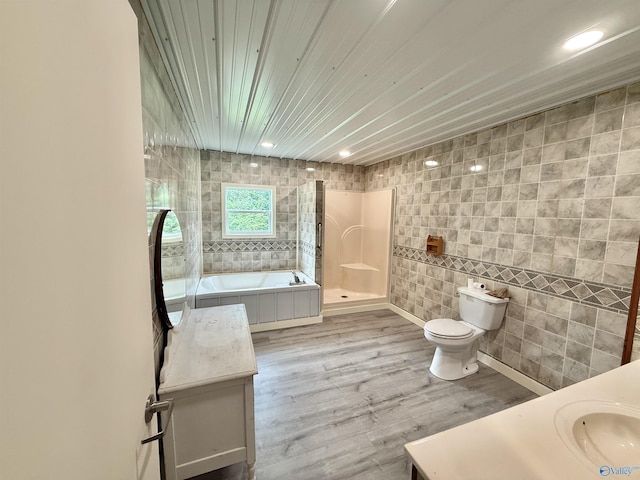 full bath featuring a tub, tile walls, walk in shower, vanity, and toilet