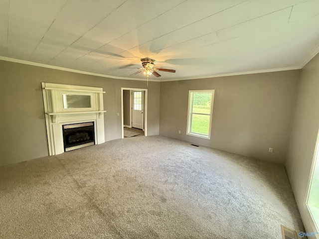 unfurnished living room with ceiling fan, visible vents, a fireplace, ornamental molding, and carpet