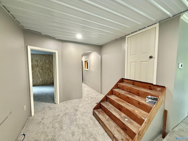 staircase featuring arched walkways and carpet