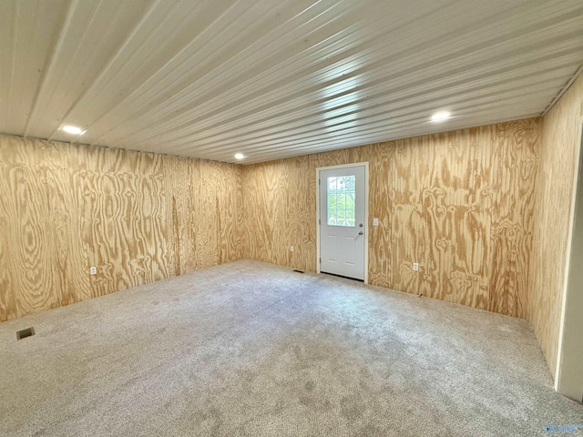carpeted empty room with wood walls