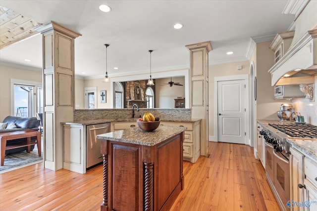 kitchen with light wood-style flooring, decorative light fixtures, stainless steel appliances, a peninsula, and crown molding