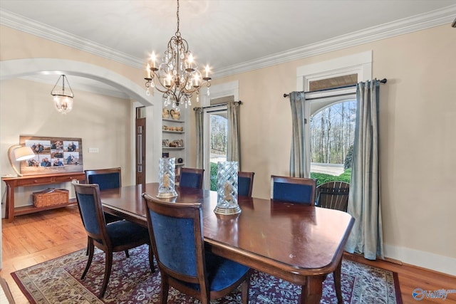 dining area with a wealth of natural light, a notable chandelier, arched walkways, and wood finished floors