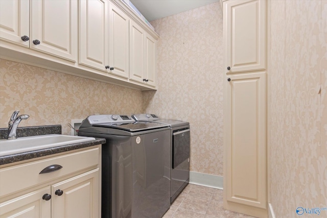 laundry area with baseboards, wallpapered walls, cabinet space, a sink, and washer and dryer