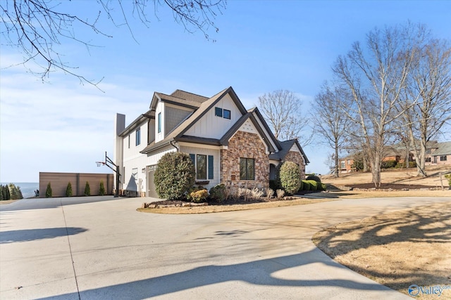 craftsman-style house featuring stone siding, curved driveway, board and batten siding, and a garage