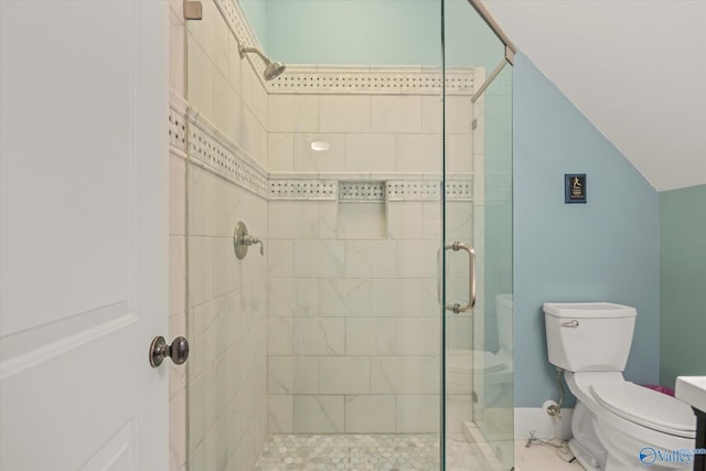 bathroom with a stall shower, toilet, and vaulted ceiling