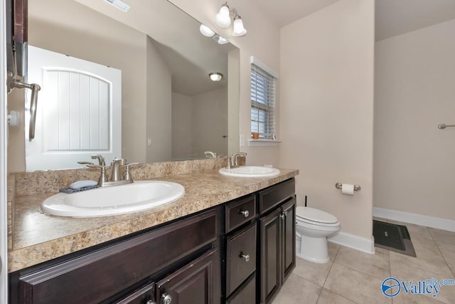 full bath featuring double vanity, a sink, toilet, and tile patterned floors