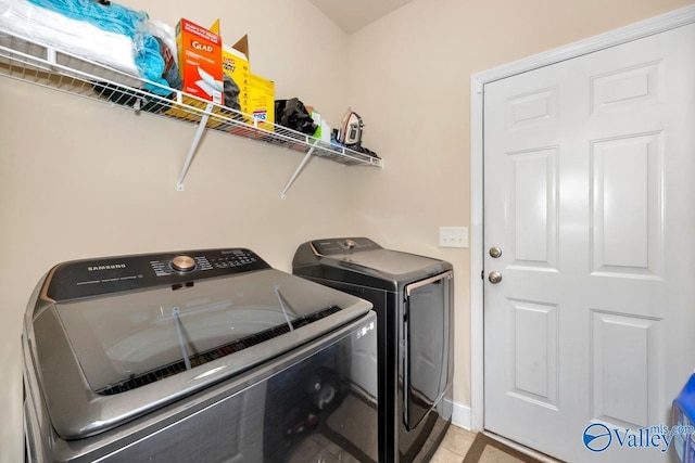 clothes washing area with washing machine and dryer, laundry area, and light tile patterned floors