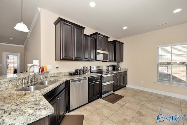 kitchen featuring appliances with stainless steel finishes, light stone countertops, crown molding, a sink, and recessed lighting