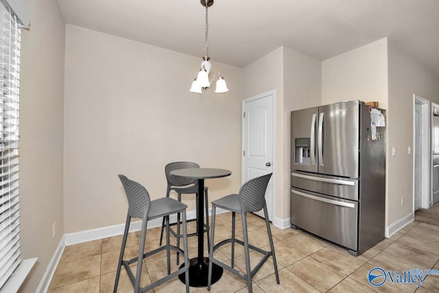 kitchen with light tile patterned floors, a notable chandelier, baseboards, stainless steel refrigerator with ice dispenser, and pendant lighting