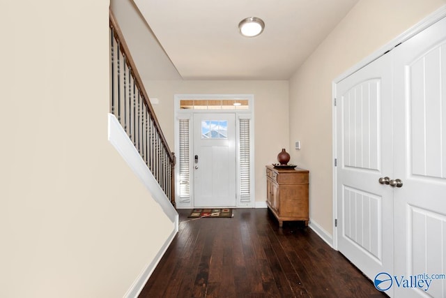 foyer entrance featuring stairway, hardwood / wood-style flooring, and baseboards