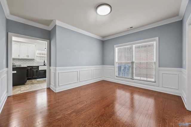 11 Nandina Ln SW, Huntsville, AL 35824 - unfurnished room featuring light wood-type flooring, a wainscoted wall, crown molding, a decorative wall, and a sink