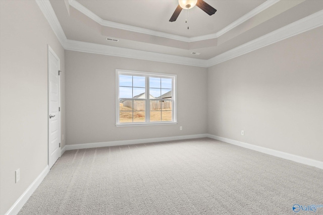 carpeted spare room with a raised ceiling, ceiling fan, and crown molding