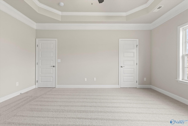 carpeted empty room with a tray ceiling, crown molding, and plenty of natural light