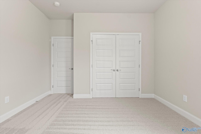 unfurnished bedroom featuring a closet and light colored carpet