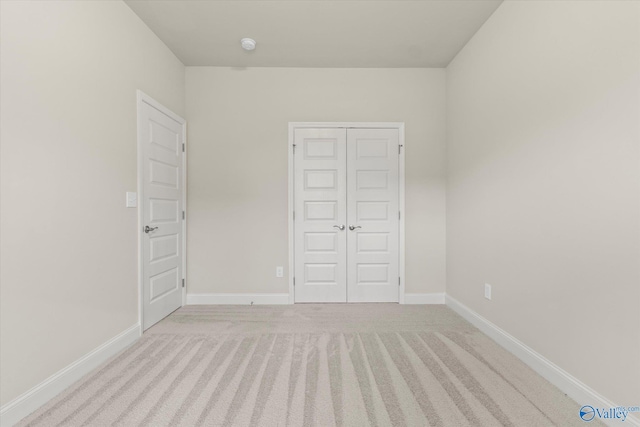 unfurnished bedroom with light colored carpet and a closet