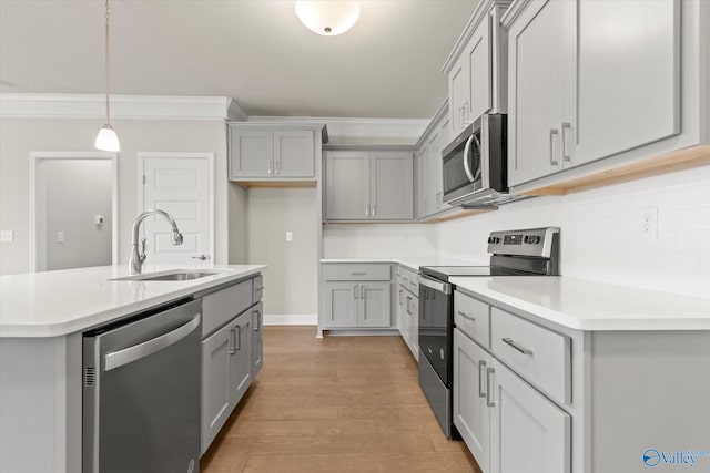 kitchen featuring appliances with stainless steel finishes, gray cabinetry, sink, pendant lighting, and light hardwood / wood-style flooring