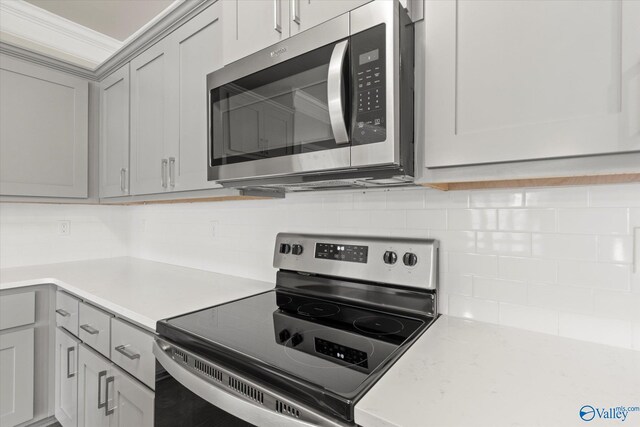 kitchen with gray cabinetry, backsplash, and stainless steel appliances