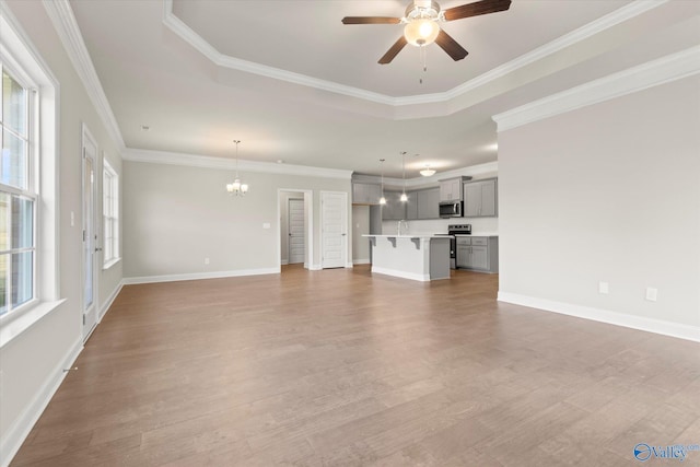 unfurnished living room featuring hardwood / wood-style floors, ceiling fan with notable chandelier, a healthy amount of sunlight, and ornamental molding