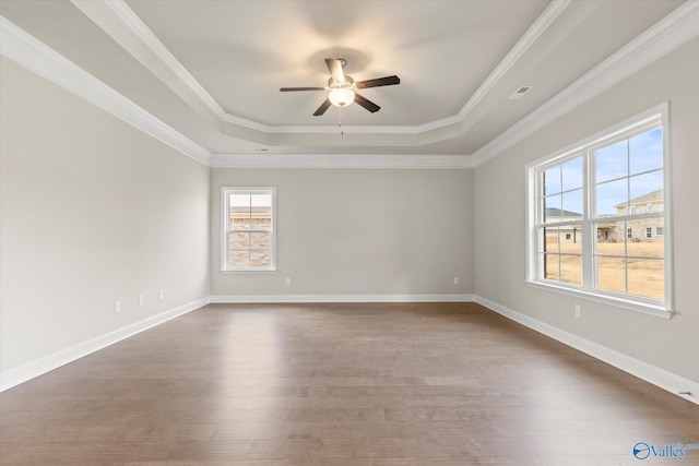 spare room featuring hardwood / wood-style flooring, ceiling fan, ornamental molding, and a tray ceiling