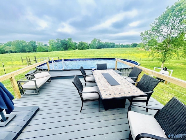 wooden terrace featuring outdoor dining space, a yard, a rural view, and an outdoor pool