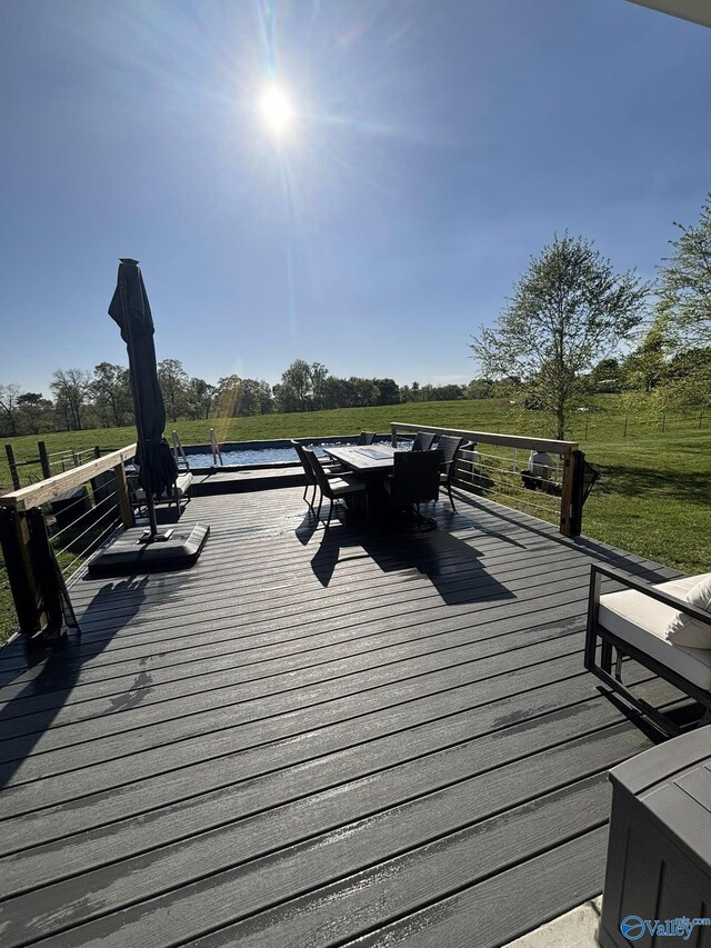 wooden terrace featuring outdoor dining space, a yard, and a rural view