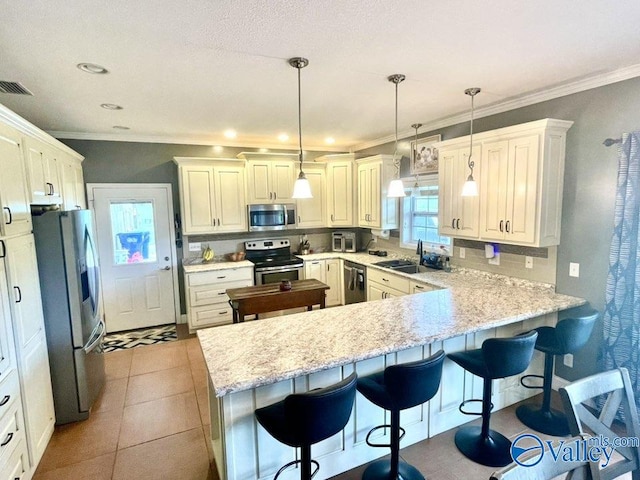 kitchen with ornamental molding, a breakfast bar, stainless steel appliances, and a peninsula