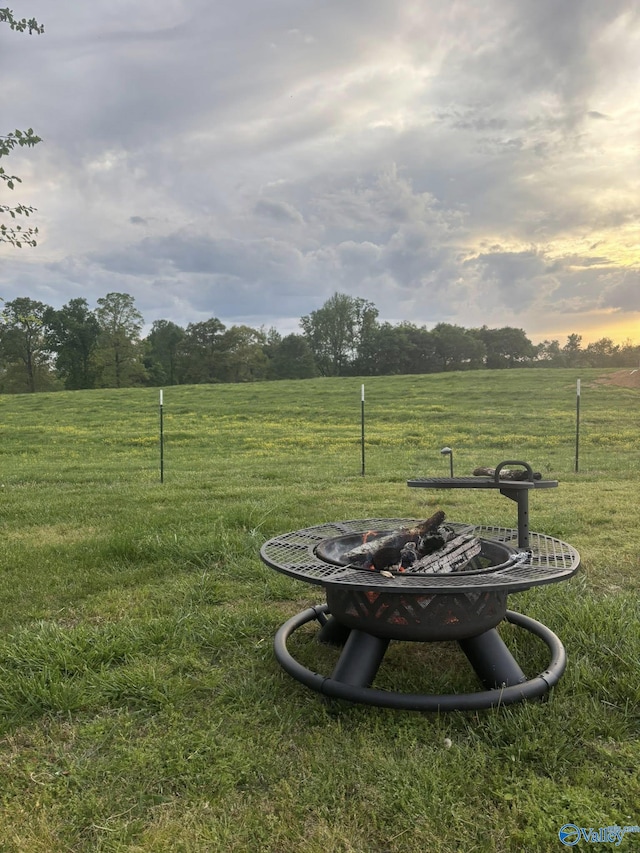 yard at dusk featuring a rural view and an outdoor fire pit